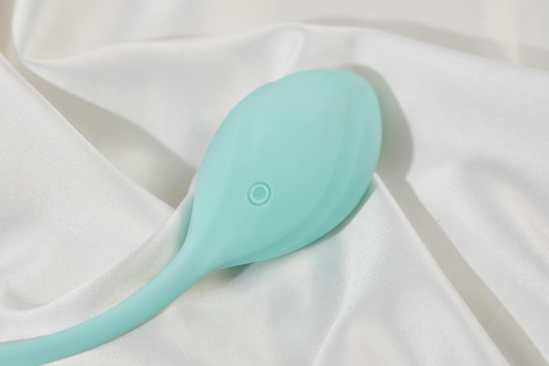 A sleek lemon-colored clitoral suction vibrator on smooth white silk fabric