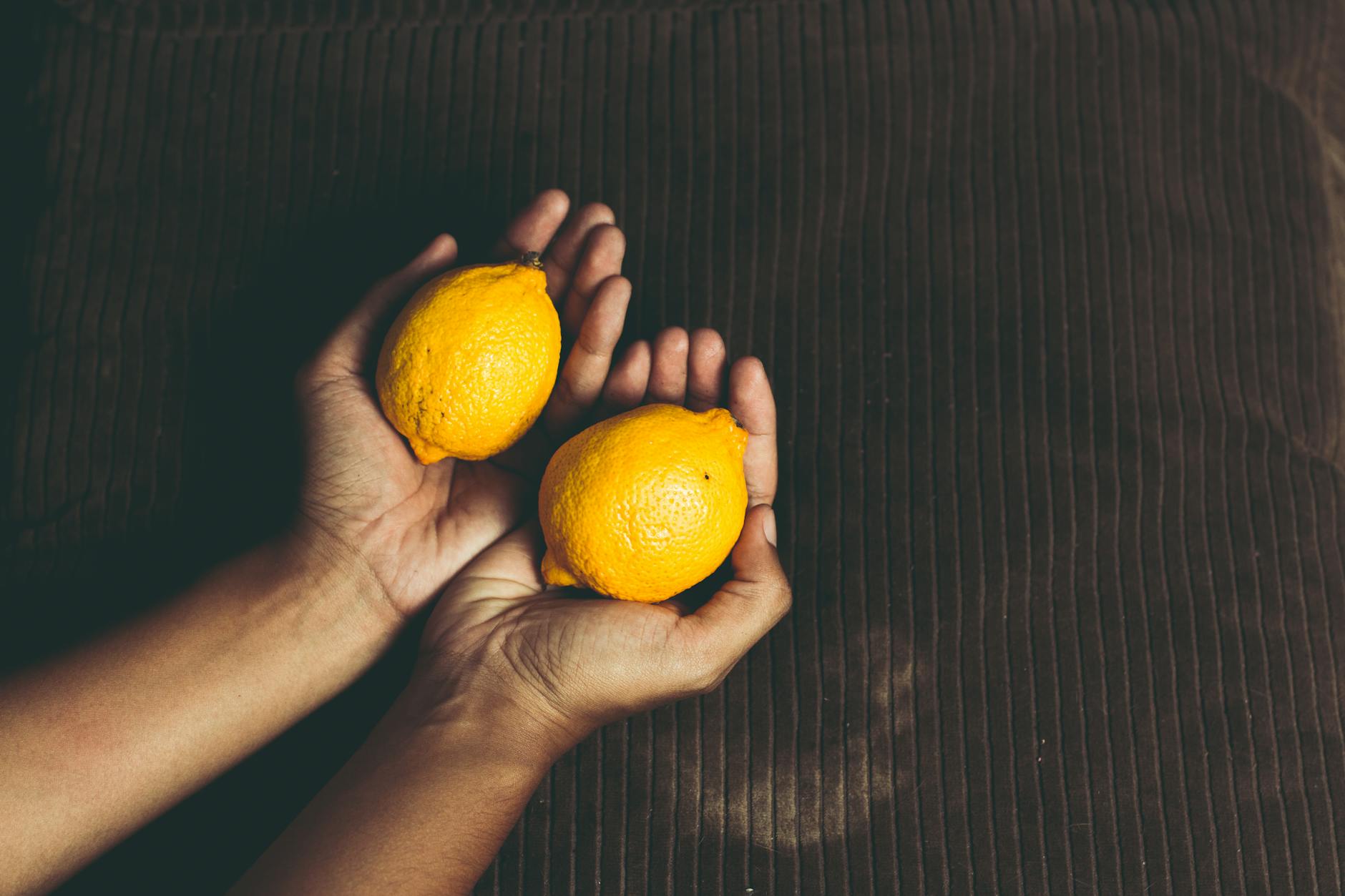 Two fresh lemons held in cupped hands, symbolizing the gentle, natural appeal of lemon-shaped vibrators