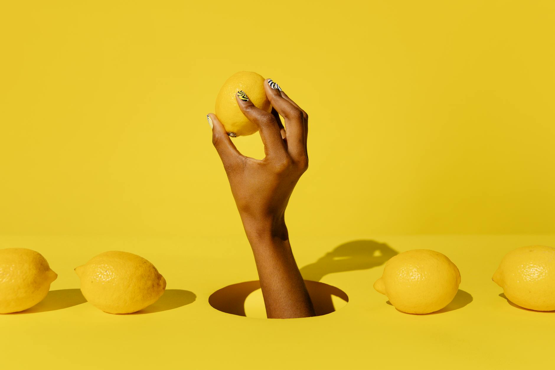 Hand holding a bright lemon against a vivid yellow background, symbolizing fresh intimacy solutions