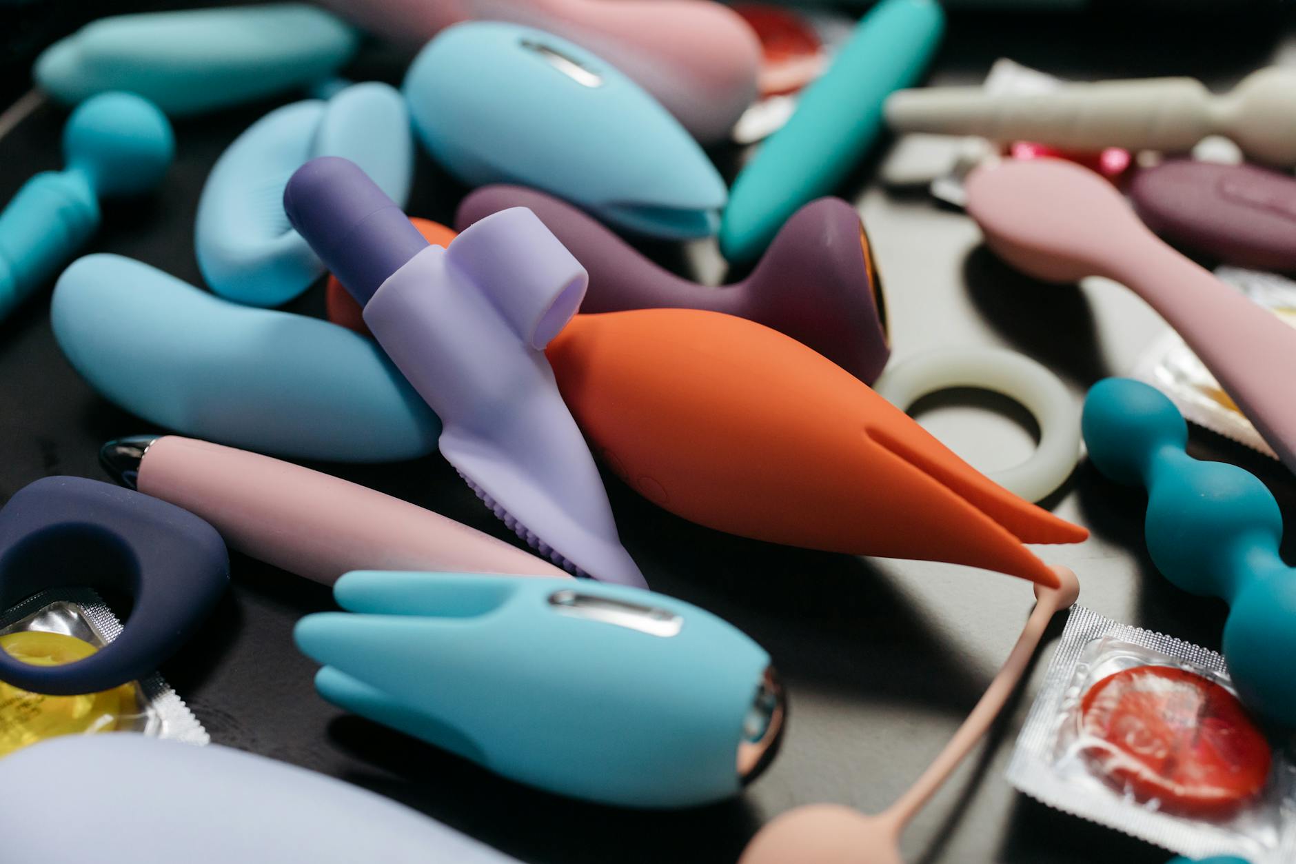 A hand holding a vibrant orange lemon vibrator against a minimalist purple background