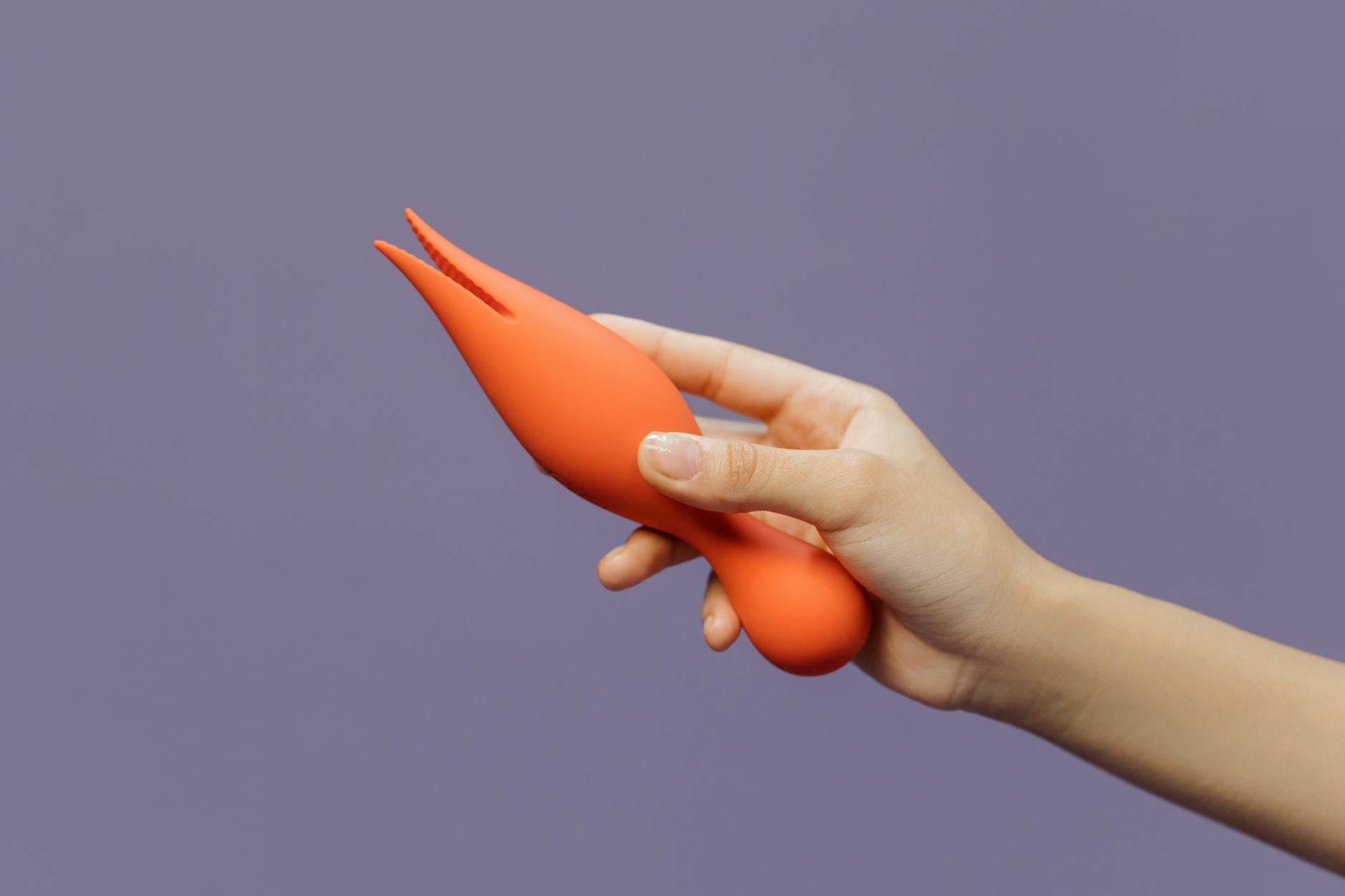 Close-up of a hand holding a lemon vibrator against a purple backdrop, illustrating sensual comfort and control.