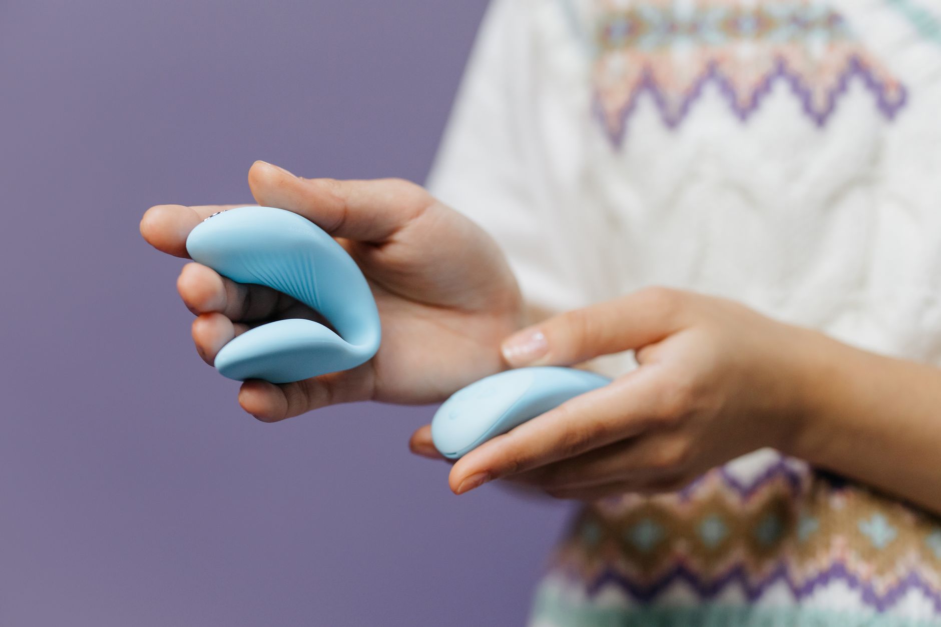 A hand holding a sleek blue vibrator against a purple background, representing renewed intimacy.