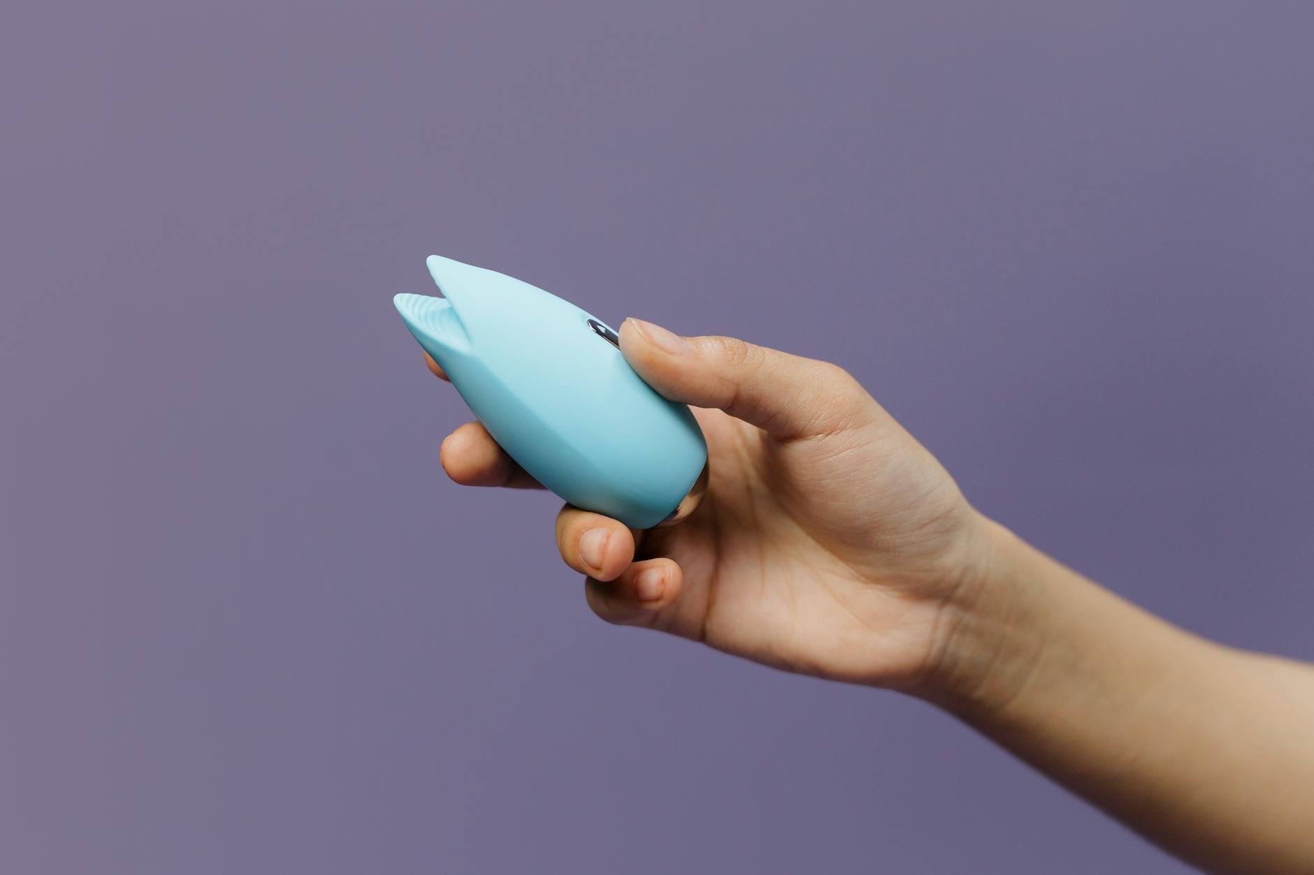 A blue silicone vibrator held in hand, representing intimate wellness during recovery